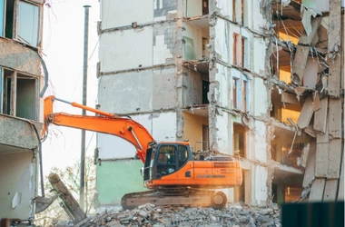 Safe Demo Dallas excavator performing controlled demolition of multi story building structure in urban area